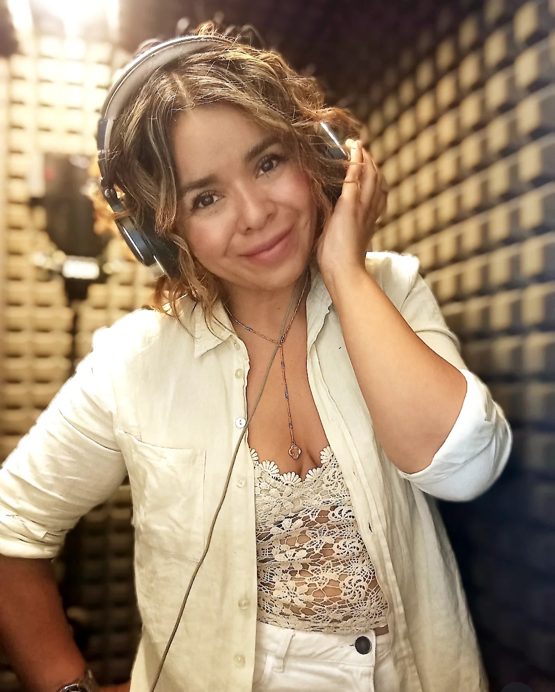 Vivi Morales smiling with headphones on, in a recording booth